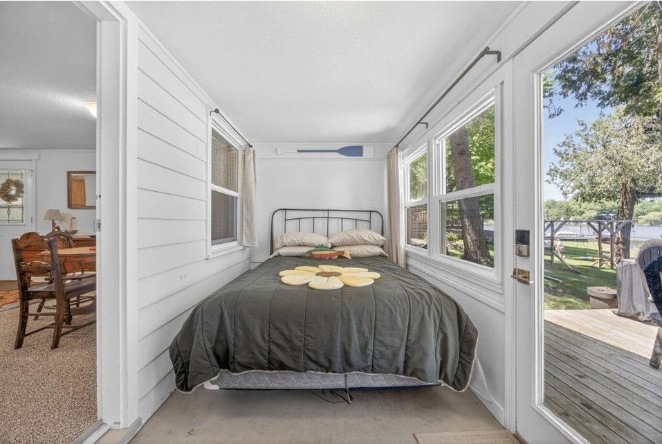 Sleeping porch with bed and French door out to the deck and lake