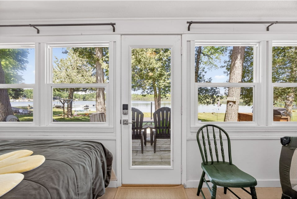Sunroom windows and French door framing Todd Lake, with Adirondack chairs on the deck