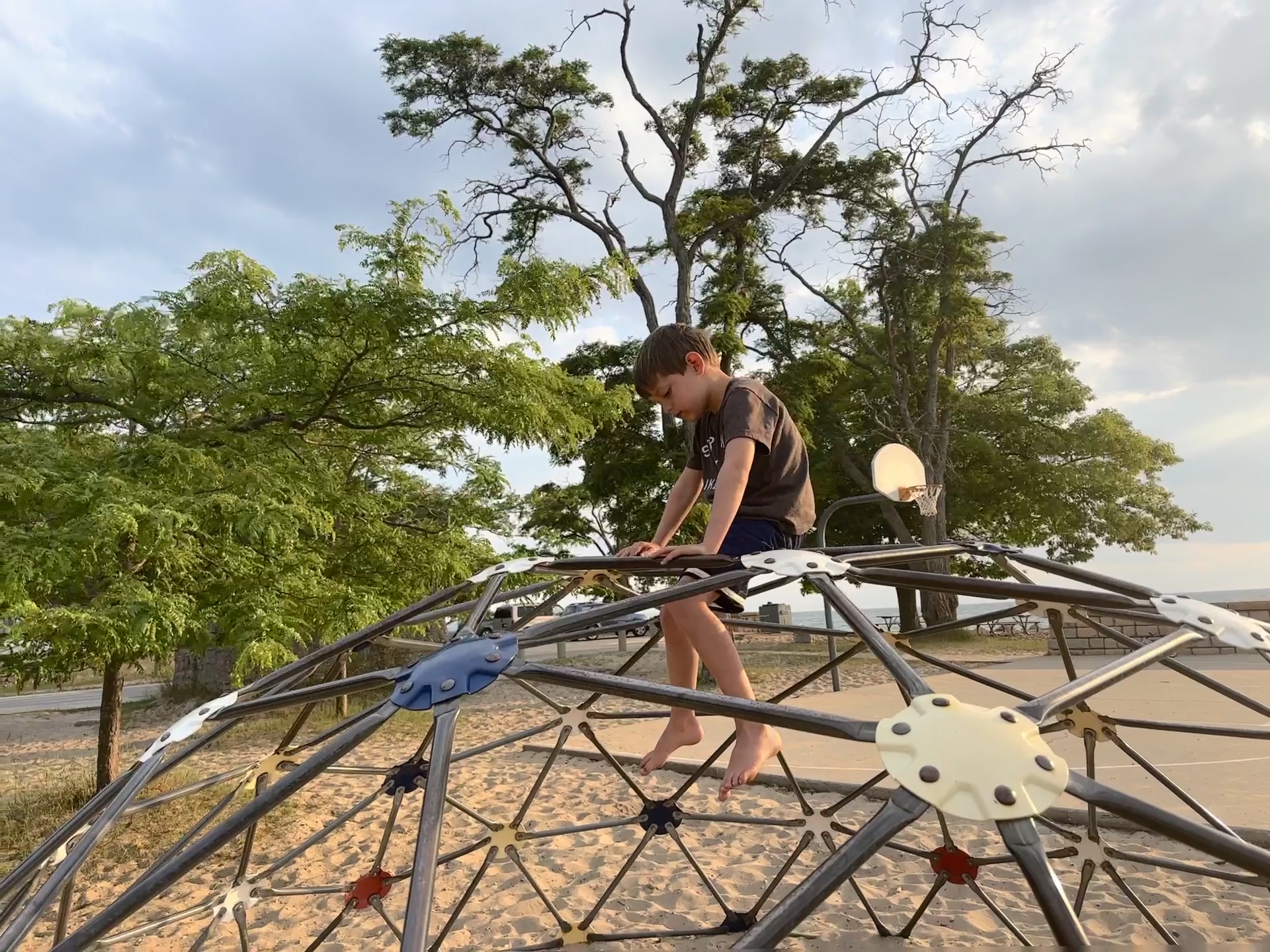 A child on a climbing dome at a beach playground along the Sleeping Bear corridor