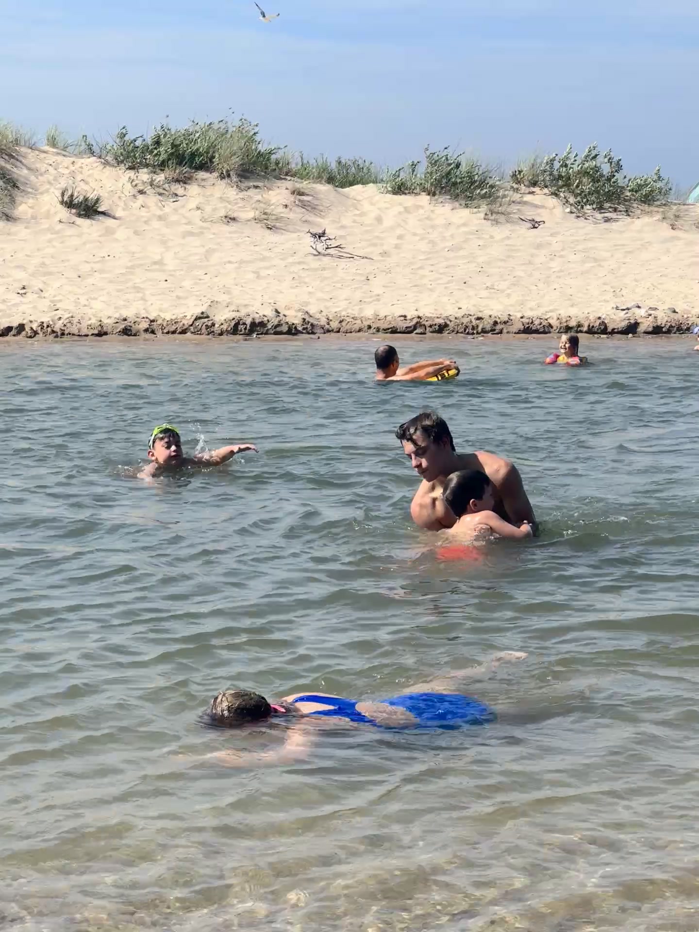 Kids swimming at the Platte River mouth, dune grass in the background