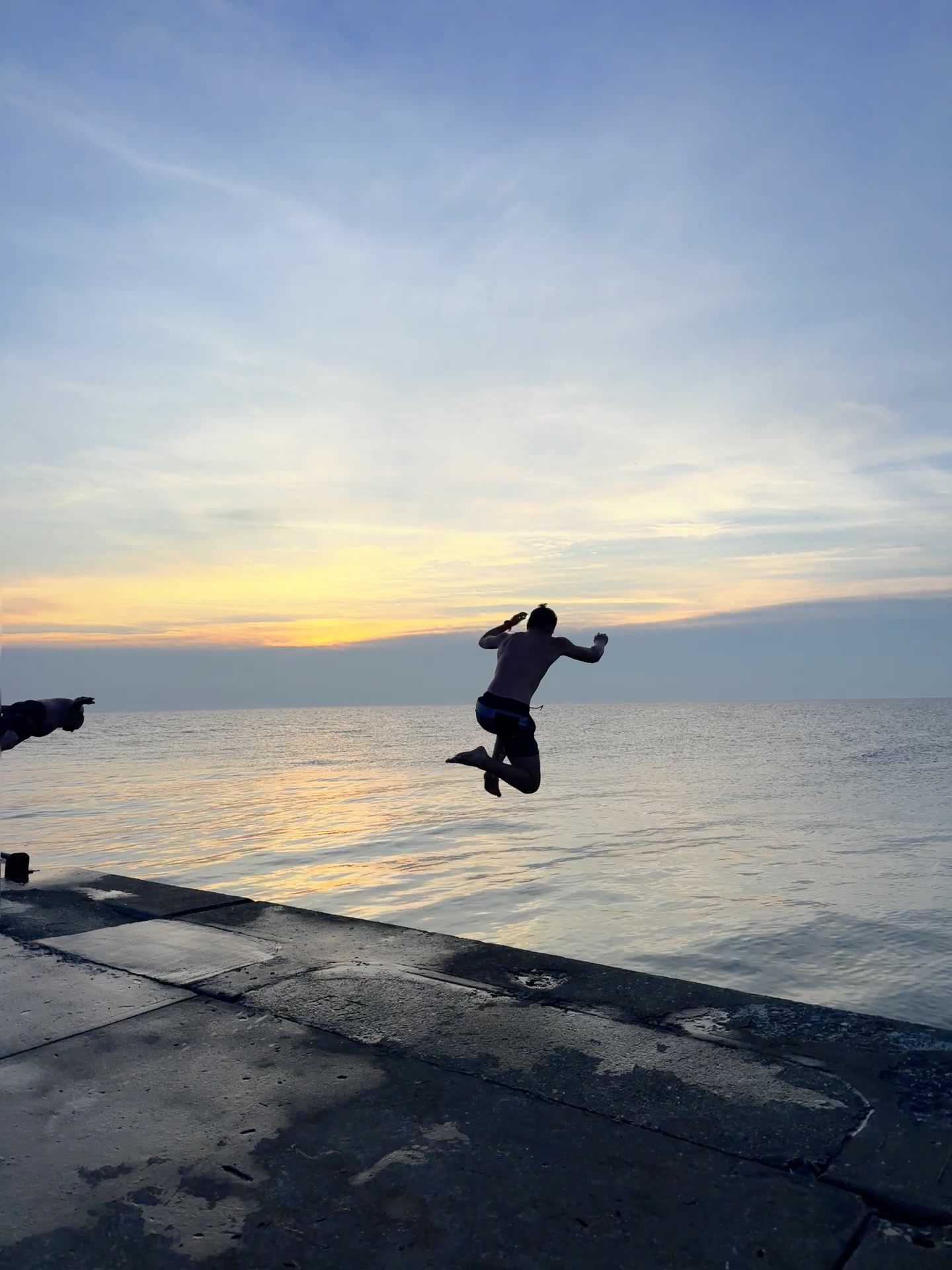Silhouette jumping from the Frankfort pier into Lake Michigan at sunset