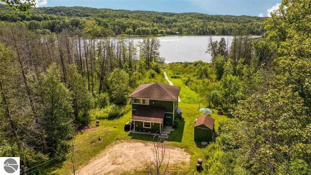 Aerial view of a green cabin on six wooded acres with Scott's Lake beyond at 3555 Wilson Road